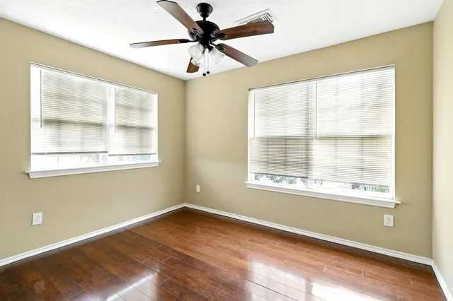 a view of an empty room with a window and wooden floor
