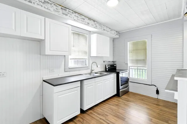a kitchen with stainless steel appliances granite countertop a sink and cabinets with wooden floor