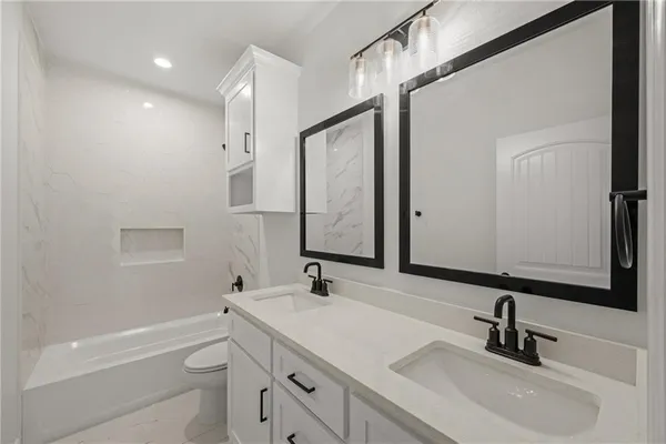 a bathroom with a sink a toilet a mirror and shower