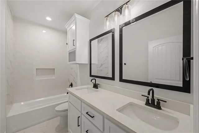 a bathroom with a sink a toilet a mirror and shower