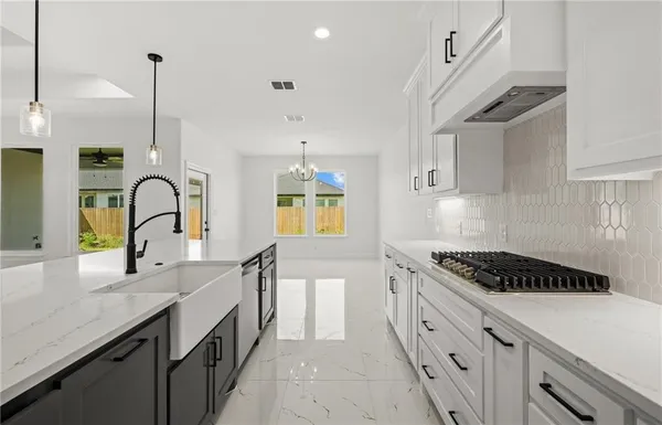 a kitchen with granite countertop a sink a stove and cabinets