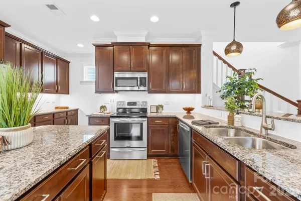 a kitchen with stainless steel appliances granite countertop a sink a stove and a refrigerator