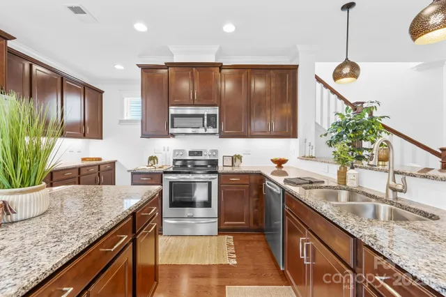 a kitchen with stainless steel appliances granite countertop a sink a stove and a refrigerator
