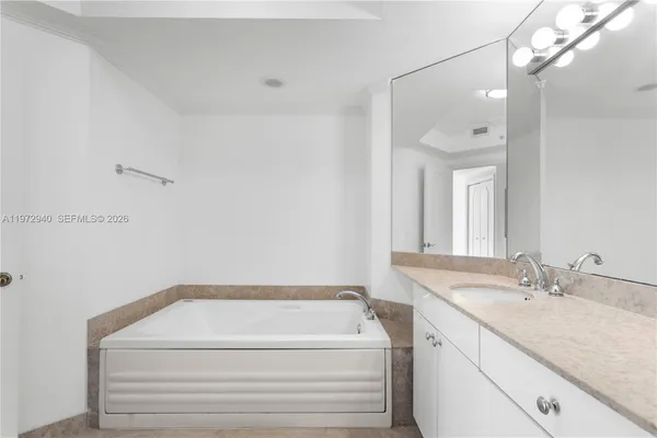 a bathroom with a granite countertop sink and a bathtub