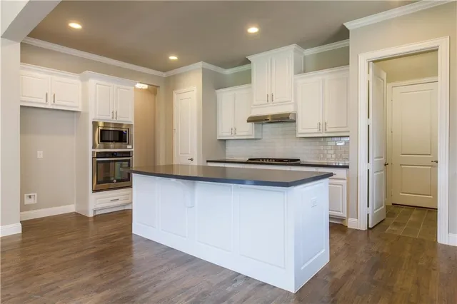 a kitchen with stainless steel appliances granite countertop a refrigerator and a stove top oven