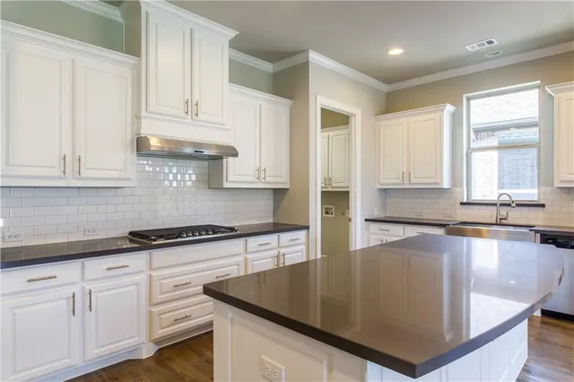 a kitchen with stainless steel appliances granite countertop a sink a stove and cabinets