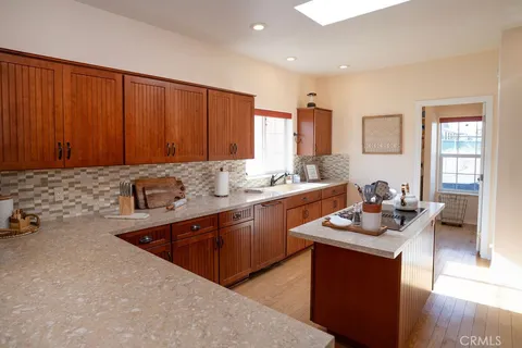 a large kitchen with kitchen island a large counter top space a sink a window and stainless steel appliances