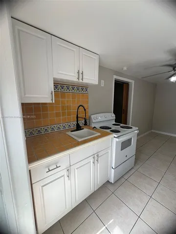 a kitchen with white cabinets and sink