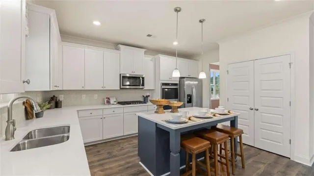 a kitchen with kitchen island stainless steel appliances a table and chairs in it