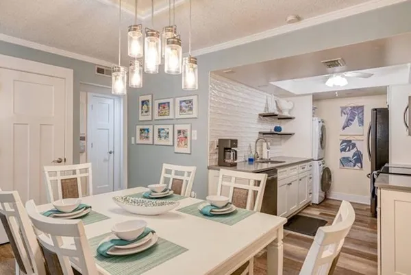 a view of a dining room with furniture a kitchen and chandelier