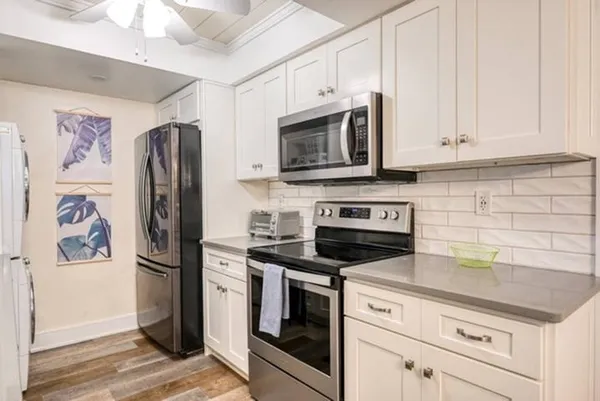 a kitchen with stainless steel appliances white cabinets and a stove a refrigerator with wooden floor