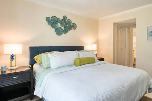 a bedroom with a bed and a lamp on dresser