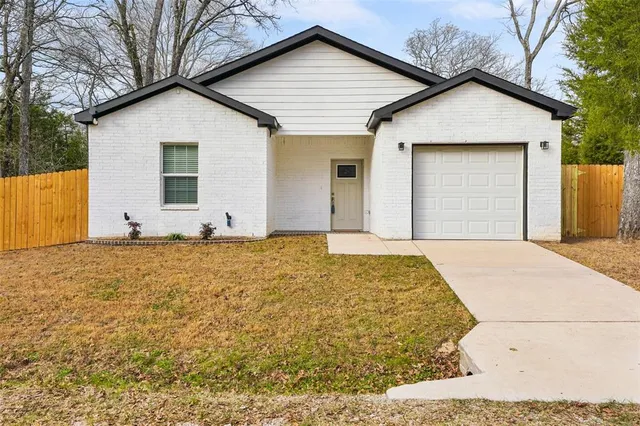 a front view of a house with white fence
