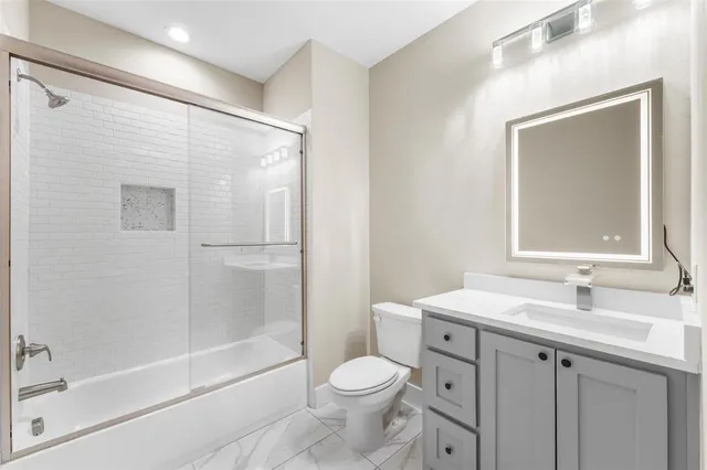 a bathroom with a shower sink vanity mirror and toilet