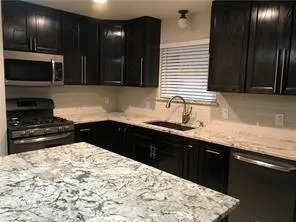 a kitchen with stainless steel appliances kitchen island granite countertop a sink stove and cabinets