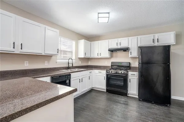 a kitchen with stainless steel appliances granite countertop a stove a refrigerator and a sink with wooden floors