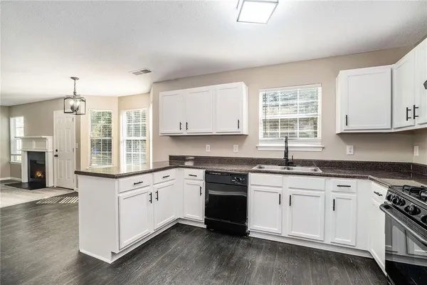 a kitchen with granite countertop white cabinets and wooden floor
