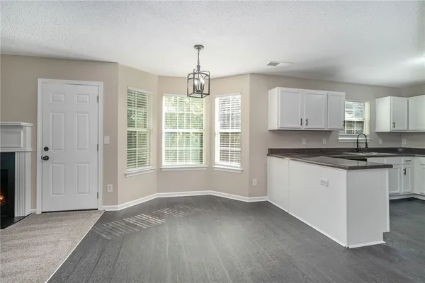 a kitchen with granite countertop a stove a sink and white cabinets with wooden floor