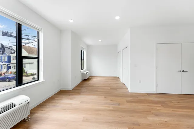 a view of an empty room with a window and wooden floor