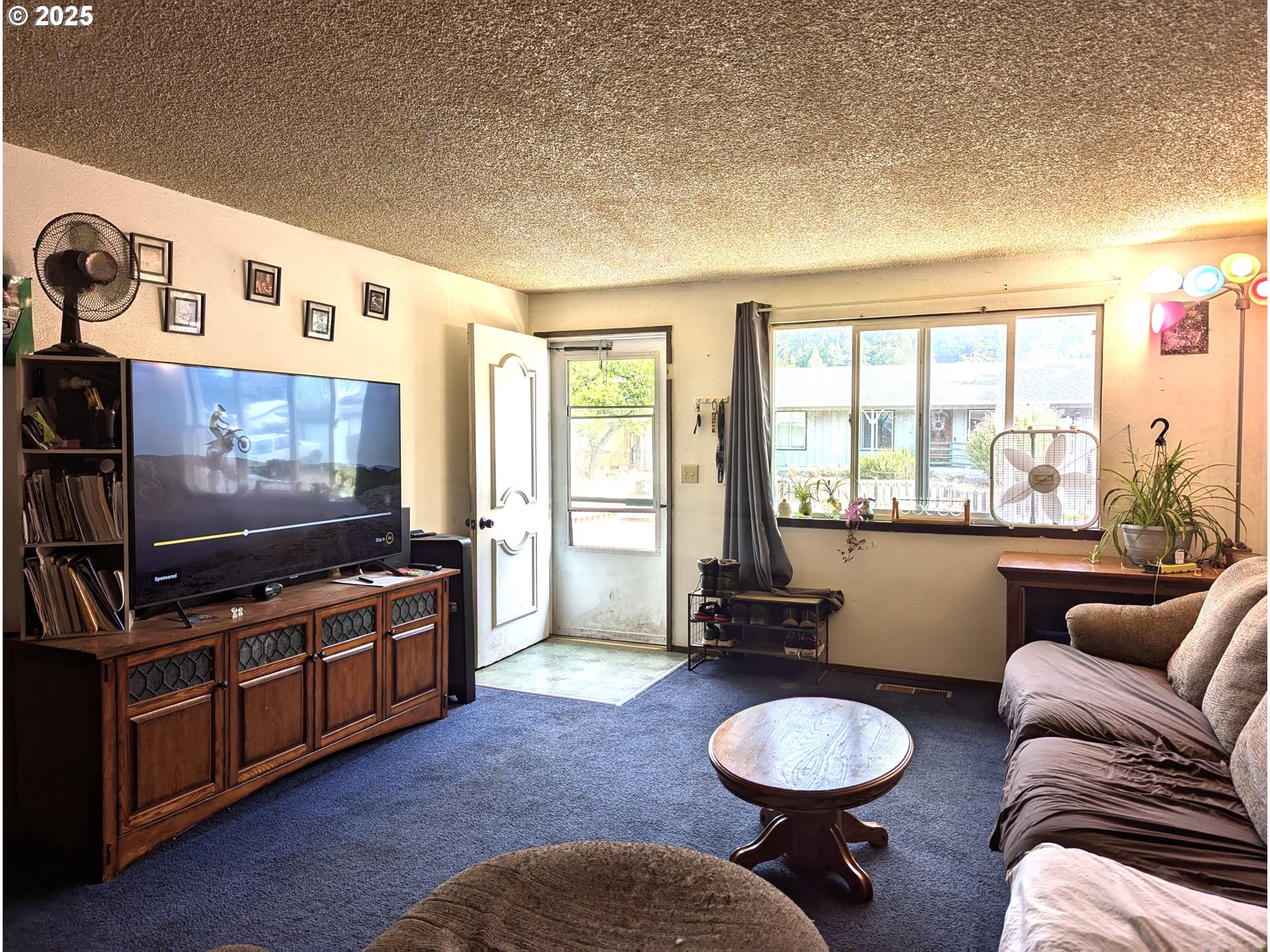 47696 West 1st Street Oakridge, OR 97463 - Photo 17 of 20 a living room with furniture a flat screen tv and a floor to ceiling window