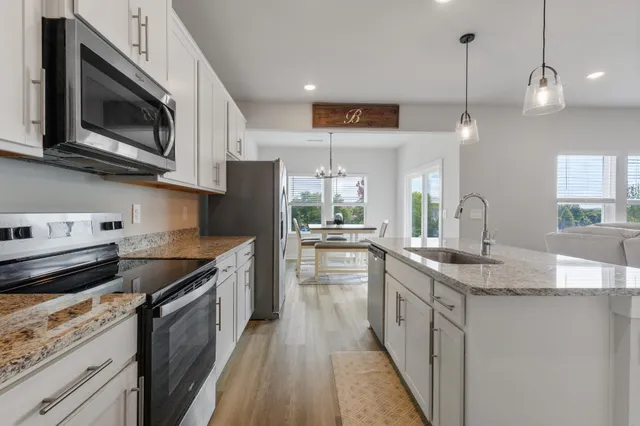 a kitchen with kitchen island granite countertop a sink a counter space stainless steel appliances and cabinets