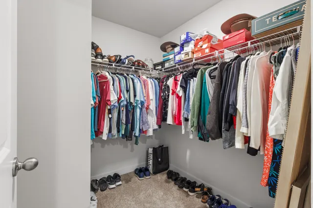 a view of walk in closet with clothes and shoes