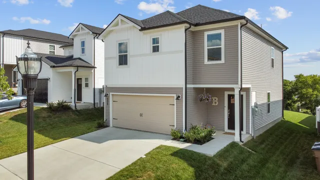 a view of a white house next to a yard with big trees