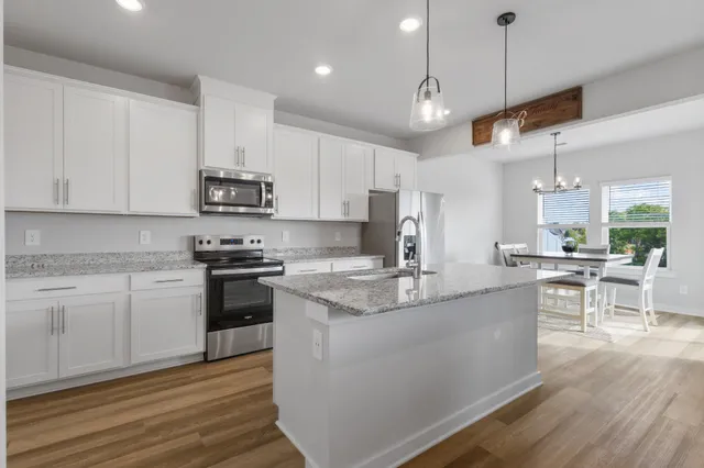 a kitchen with kitchen island granite countertop a sink cabinets and wooden floor