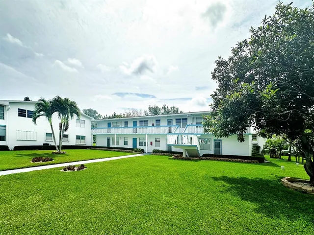 a view of a house with a big yard and palm trees
