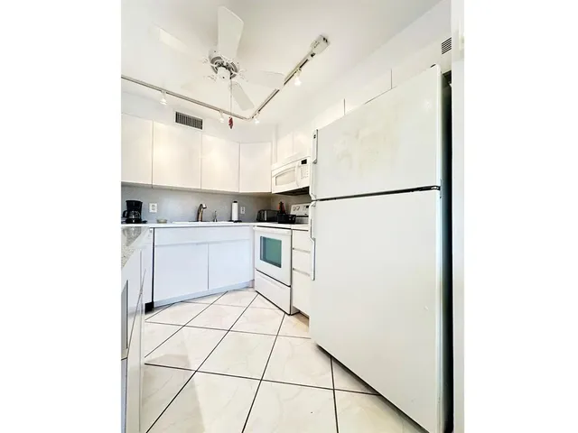 a kitchen with white cabinets and white appliances