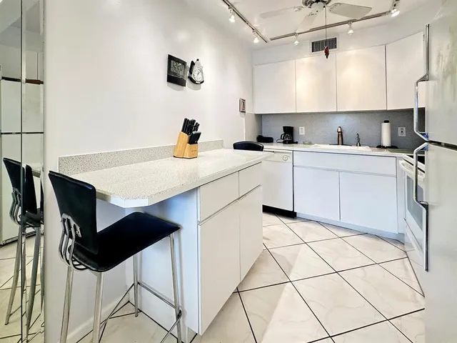 a kitchen with stainless steel appliances kitchen island a table chairs in it and white cabinets
