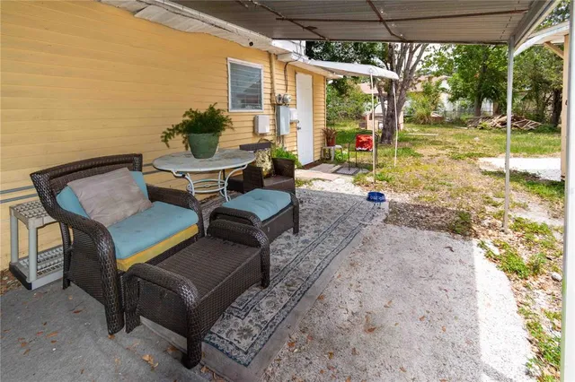 a view of a backyard with couches potted plants and a large tree