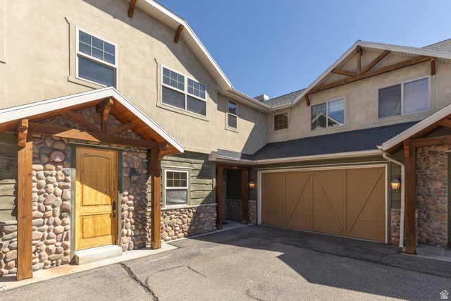 5168 Fairview Loop, Unit C604 Eden, UT 84310 - Photo 2 of 53 View of front of home featuring stone siding, stucco siding, a garage, roof with shingles, and asphalt driveway