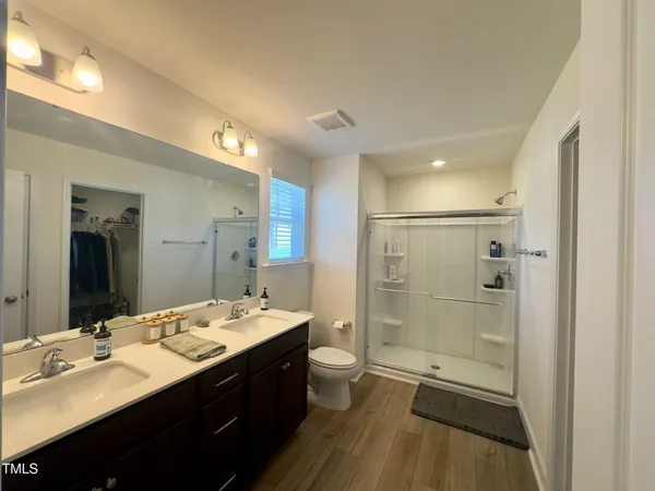 a bathroom with a double vanity sink a toilet and shower