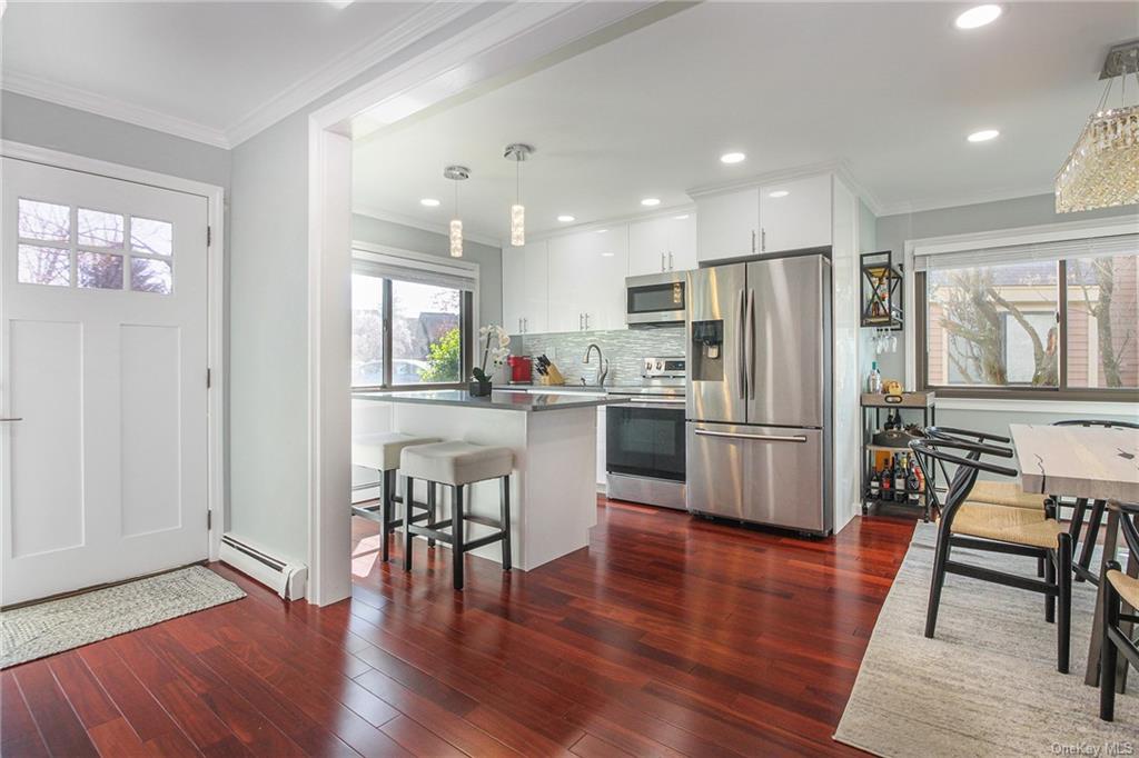 a kitchen with stainless steel appliances wooden floor and chairs