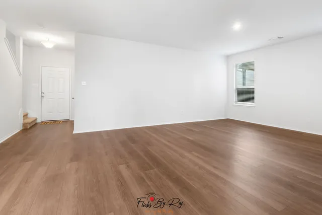 a view of empty room with wooden floor and window