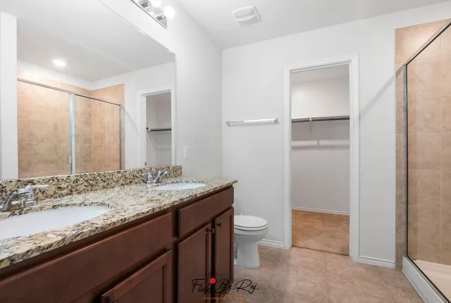 a bathroom with a granite countertop sink a toilet and shower