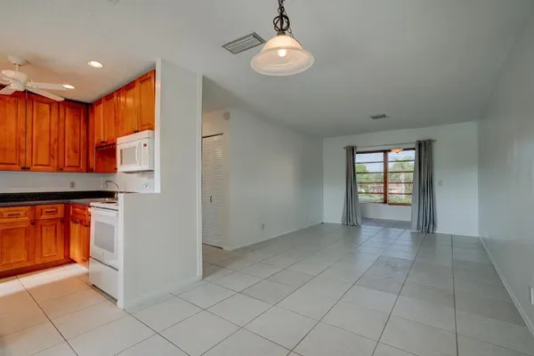an empty room with kitchen view and wooden floor