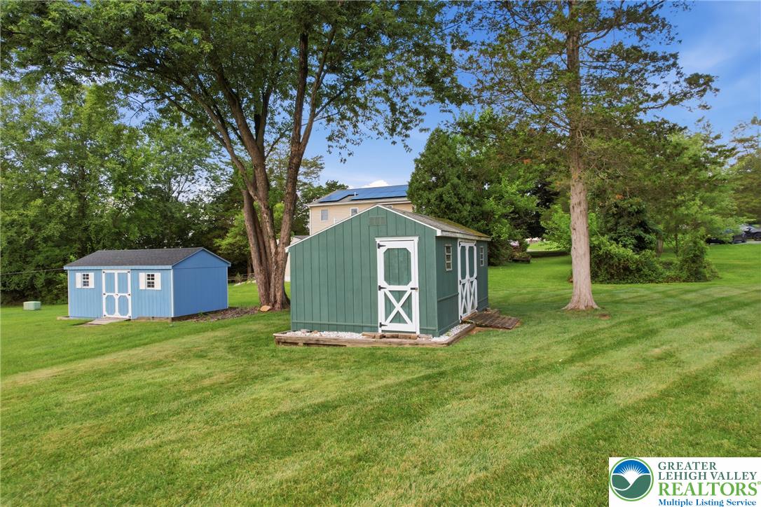 1385 Woodmere Road Pottstown, PA 19464 - Photo 49 of 57 Two well-maintained storage sheds are nestled in a verdant, expansive yard, offering practical solutions for organization.