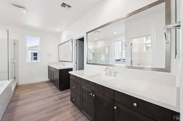 a spacious bathroom with a double vanity sink a mirror and a bathtub