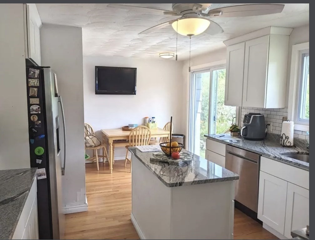 147 Forest Street Middleton, MA 01949 - Photo 3 of 32 a kitchen with stainless steel appliances granite countertop a sink dishwasher a microwave oven and a dining table with wooden floor