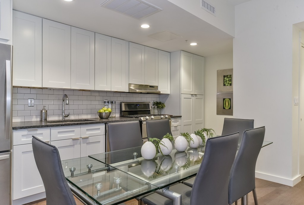 a kitchen with a dining table chairs and white cabinets