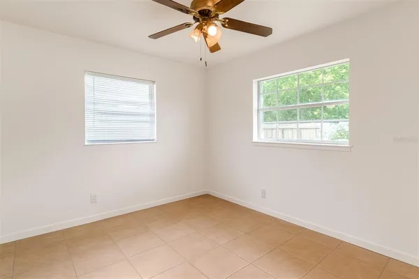 an empty room with a window and a fan