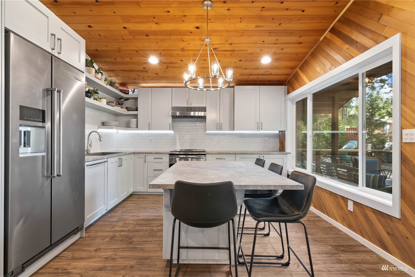 51 East Canyon View Road Belfair, WA 98528 - Photo 2 of 35 a kitchen with stainless steel appliances granite countertop a stove a refrigerator a microwave oven with a dining table and chairs with wooden floor