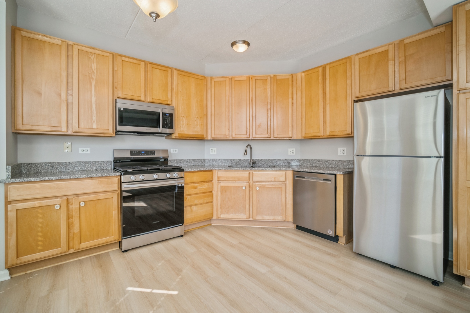715 Astor Lane, Unit 402 Wheeling, IL 60090 - Photo 4 of 12 a kitchen with granite countertop white cabinets and stainless steel appliances
