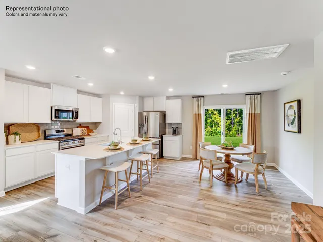 a kitchen with sink a stove and white cabinets with wooden floor