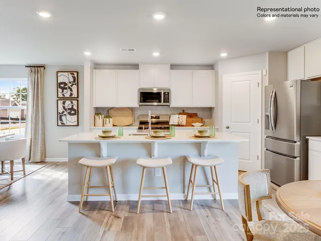 a living room with stainless steel appliances furniture and a wooden floor