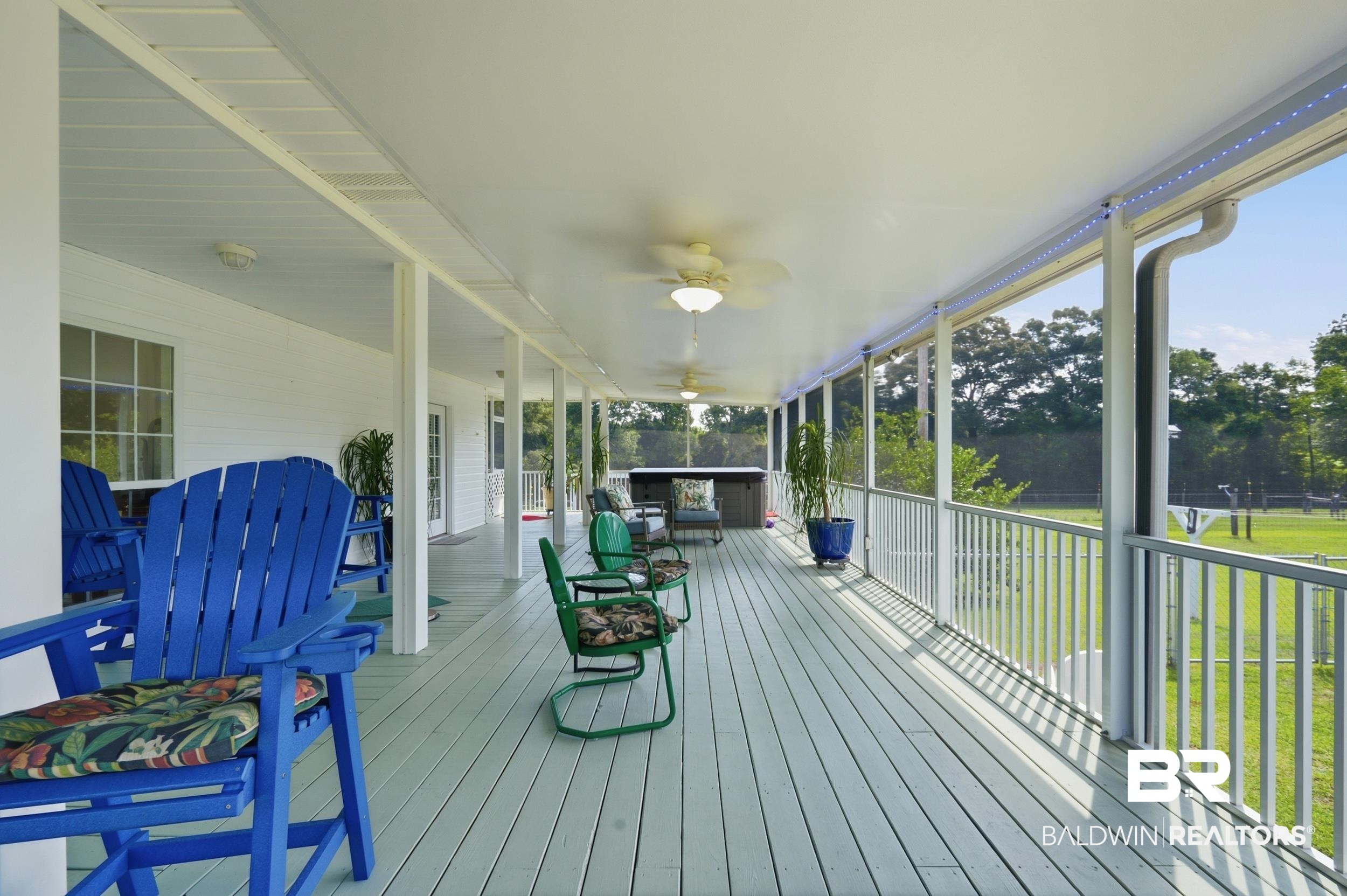 15855 Calvin Richerson Road Bay Minette, AL 36507 - Photo 15 of 83 Expansive covered porch featuring a painted wood-finish deck, multiple ceiling fans, recessed lighting, and white railings overlooking a grassy area