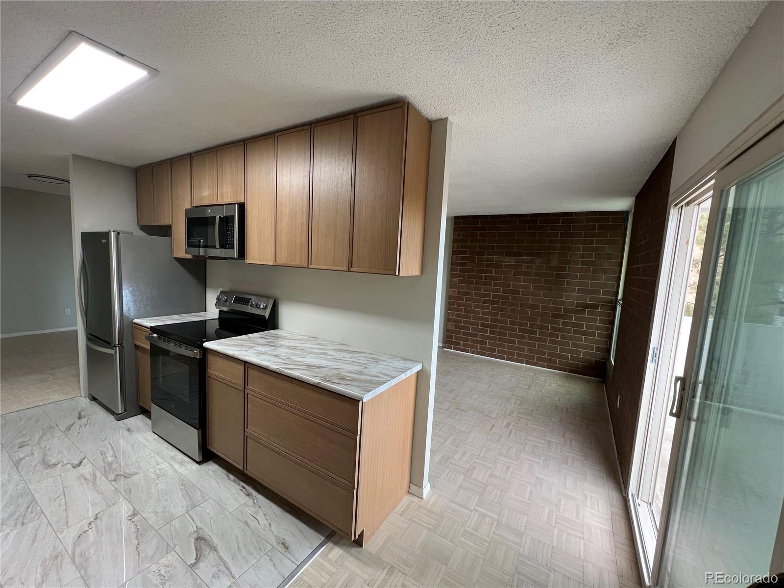 2880 South Locust Street, Unit 507S Denver, CO 80222 - Photo 7 of 48 a kitchen with granite countertop a refrigerator and a stove top oven