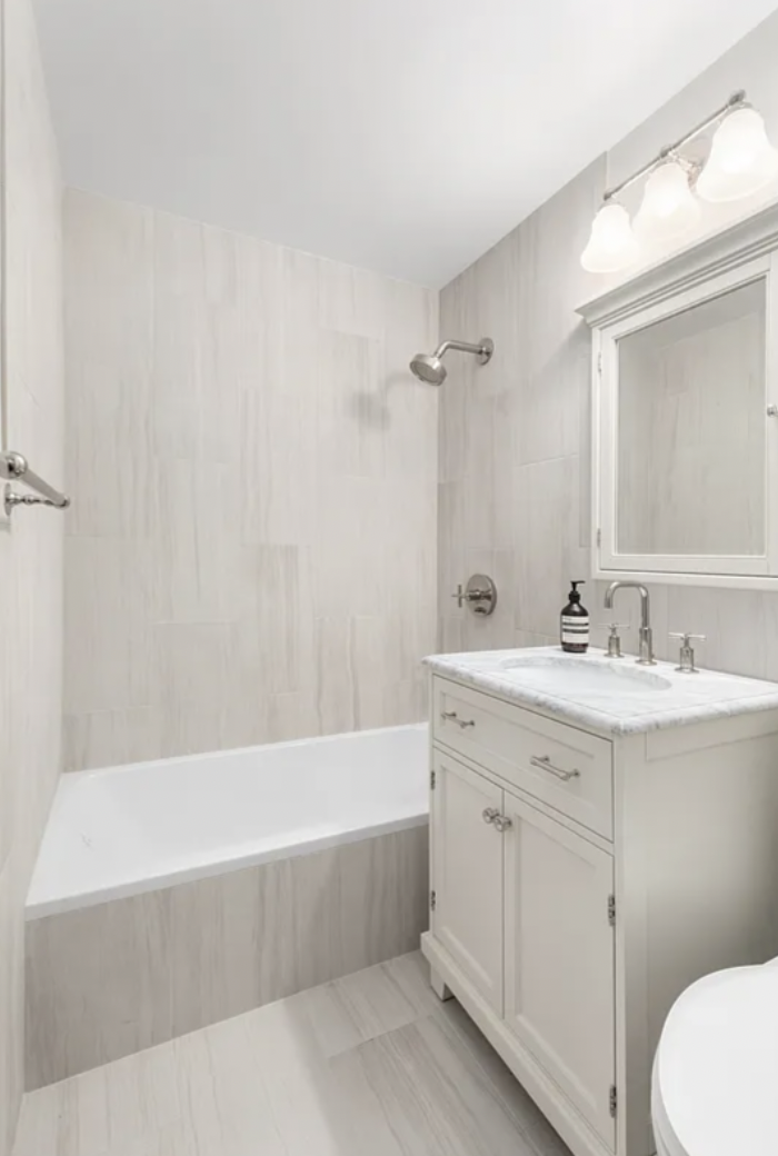 625 Main Street, Unit 1432 Manhattan, NY 10044 - Photo 7 of 12 a bathroom with a bathtub a sink a toilet a mirror and vanity